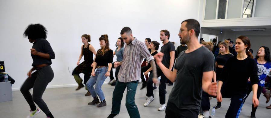 Gran grupo de empleados bailando reggaeton en línea durante un team building en Barcelona - line dance colectiva en un estudio con espacio